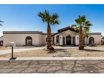 Charming single-story home featuring desert landscaping, palm trees, and a private driveway under a bright blue sky at 12805 W Colter St, Litchfield Park, AZ 85340