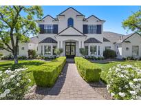 Elegant two-story home featuring a well-manicured lawn, lush greenery, and a charming brick pathway to the front door at 23902 S 202Nd Ct, Queen Creek, AZ 85142