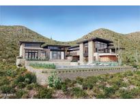 Stunning modern home featuring stone accents, black trim, large windows, and a luxurious pool with desert landscaping at 3367 N Highlands Dr # 39, Buckeye, AZ 85396