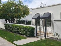 Charming white home with a lush lemon tree, trimmed hedges, and a black wrought iron gate at 4830 N 72Nd Way, Scottsdale, AZ 85251