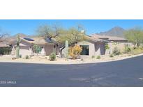 Stunning single-story home featuring a two-car garage, solar panels, desert landscaping, and mountain views at 10694 E Firethorn Dr, Scottsdale, AZ 85255