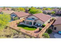 Aerial view of backyard with artificial turf, covered patio, and outdoor furniture in a desert landscape at 17514 W Desert Sage Dr, Goodyear, AZ 85338
