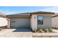 A modern home featuring a gray garage door, neutral stucco and siding and a brick driveway at 20332 W Sells Dr, Buckeye, AZ 85396