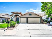 Charming home with a two-car garage, tiled roof, and a well-manicured front yard at 1835 E Marquette Dr, Gilbert, AZ 85234