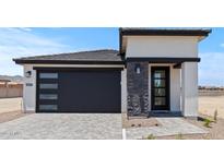 Stylish home exterior features a modern garage door, stone accents, and a welcoming entrance at 20326 W Roma Ave, Buckeye, AZ 85396