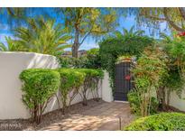 Charming courtyard gate entrance adorned with lush greenery and brick pathway leading into the property at 5838 E Berneil Ln, Paradise Valley, AZ 85253
