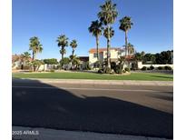 Charming two-story home featuring lush landscaping, a well-manicured lawn, and elegant curb appeal with mature palm trees at 6337 W Deer Valley Rd, Glendale, AZ 85308