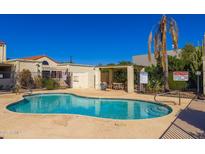 Community pool area featuring a clear blue pool, a shaded seating area, and desert landscaping under a bright blue sky at 15801 N 29Th St # 16, Phoenix, AZ 85032