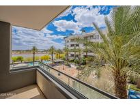 This balcony offers a relaxing view of the pool, palm trees, and community lake under a sunny sky at 945 E Playa Del Norte Dr # 3002, Tempe, AZ 85288