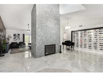 Spacious living room with tiled floors, fireplace, piano and a wine rack is great for entertaining at 102 S Honeysuckle Ln, Gilbert, AZ 85296