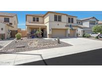 Two-story stucco home featuring a three-car garage, desert landscaping, and covered front porch at 30185 W Flower St, Buckeye, AZ 85396