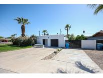 Modern home featuring a two-car garage, complemented by lush desert landscaping and clear blue skies at 519 E El Camino Dr, Phoenix, AZ 85020