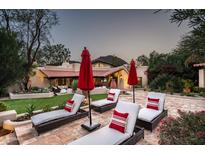Relaxing backyard patio with lounge chairs, red umbrellas, and views of the surrounding landscape at 6019 N 62Nd Pl, Paradise Valley, AZ 85253