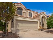 Two-story home with a beige stucco exterior, red tile roof, and a large two-car garage with a classic architectural style at 826 W Devon Dr, Gilbert, AZ 85233