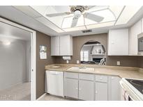 Bright kitchen features white cabinetry, a cozy pass-through window, and laminate countertops at 1217 N Miller Rd # 32, Scottsdale, AZ 85257