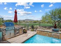 An outdoor kitchen and swimming pool overlook a golf course in this backyard oasis at 1788 W Dion Dr, Anthem, AZ 85086