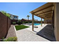 Resort-style backyard with a sparkling pool, fire pit, covered patio, and lush landscaping, perfect for entertaining at 17947 W Jojoba Rd, Goodyear, AZ 85338