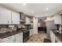 Updated kitchen with modern stainless steel appliances and tiled backsplash, adjacent to a cozy living area at 18016 N 145Th Ave, Surprise, AZ 85374