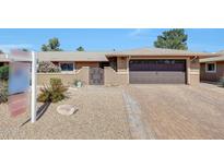 Charming home with brick driveway, two-car garage, gated entryway, and desert landscaping in the front yard at 19215 N Concho Cir, Sun City, AZ 85373