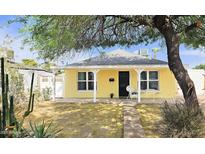 Charming yellow home featuring a covered front porch, well-kept yard, and mature tree at 227 N Morris --, Mesa, AZ 85201