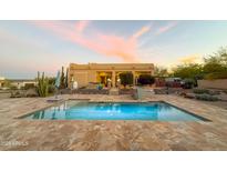 Backyard pool with tiled deck and desert landscaping at sunset at 29619 N 142Nd Pl, Scottsdale, AZ 85262