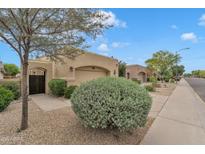Tan home with a two-car garage and iron gate, complemented by desert landscaping and a blue sky at 4545 E Wescott Dr, Phoenix, AZ 85050