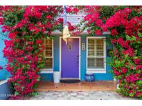 Charming home featuring a blue exterior with vibrant bougainvillea, a purple door, and tiled front porch at 512 W Roma Ave, Phoenix, AZ 85013