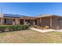 Charming single-story home featuring desert landscaping, solar panels, and a cozy pergola-covered patio at 10449 W Tropicana Cir, Sun City, AZ 85351