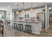 Modern kitchen with stainless steel appliances, a large island with seating, and pendant lighting at 22491 E Mewes Rd, Queen Creek, AZ 85142