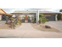 Charming home featuring unique yard decor, brickwork, and a gray garage door at 4009 S Siesta Ln, Tempe, AZ 85282