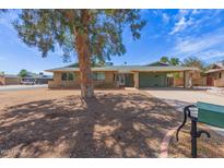 Charming single-story brick home featuring a carport and mature shade tree in the front yard under a sunny blue sky at 7126 N 29Th Dr, Phoenix, AZ 85051