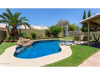 Beautiful in-ground pool with rock features, lush landscaping, and lounge area for relaxing outdoors at 1560 E Flint St, Chandler, AZ 85225
