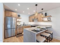 Kitchen with light wood cabinets, stainless steel appliances, pendant lighting, and a counter with barstool seating at 3033 N 39Th St # 5, Phoenix, AZ 85018
