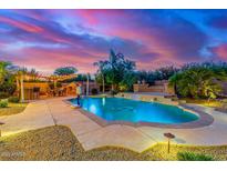 Inviting pool with waterfall feature, bar and desert landscaping under colorful sky at 4822 E Charleston Ave, Scottsdale, AZ 85254