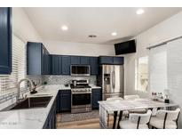 Modern kitchen features navy cabinets, stainless steel appliances, white countertops and a dining table at 10239 W Via Del Sol -- # 400, Peoria, AZ 85383