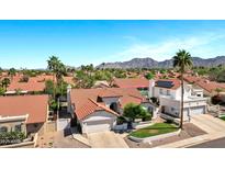 Stunning aerial view of a home with a red tile roof, solar panels, and mountain views in the distance at 10102 E Dreyfus Ave, Scottsdale, AZ 85260