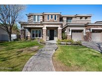 Inviting two-story home with stone accents, manicured lawn, and three-car garage, blending elegance and practicality at 2988 E Comstock Dr, Gilbert, AZ 85296