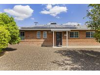 Charming brick home featuring a well-kept yard, solar panels, and a welcoming front entrance at 3002 E Montecito Ave, Phoenix, AZ 85016