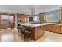 Spacious kitchen featuring wooden cabinets, a granite island with seating, and modern stainless steel appliances at 3002 E Montecito Ave, Phoenix, AZ 85016