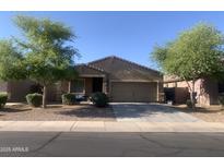 Charming single-story home featuring a two-car garage, desert landscaping, and mature trees at 38086 W Isabella Ln, Maricopa, AZ 85138