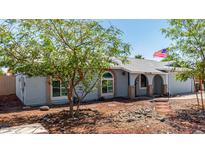 Single-story home with a light blue exterior, desert landscaping, and an American flag in the front yard at 4915 W Libby St, Glendale, AZ 85308