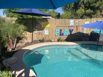 Inviting pool area with vibrant blue water, festive decorations, and tropical landscaping for backyard relaxation and entertainment at 15939 W Post Dr, Surprise, AZ 85374
