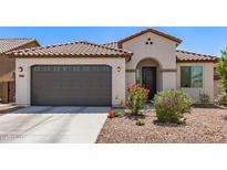 Inviting single-story home with a gray garage door, arched entry, tiled roof, and a low-maintenance landscaped front yard at 19627 W Badgett Ln, Litchfield Park, AZ 85340