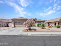 Charming single-story home featuring desert landscaping, mature trees, and a two-car garage, on a sunny day at 230 S 122Nd Ln, Avondale, AZ 85323