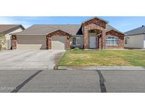 Charming single-story brick home with a three-car garage and well-maintained front yard at 4030 E Meadow Creek Way, San Tan Valley, AZ 85140