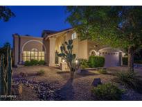 Charming home exterior with desert landscaping, stucco facade, and covered entrance at dusk at 19115 N 71St Dr, Glendale, AZ 85308