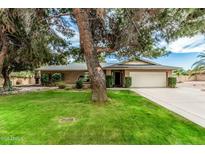 Charming single story home featuring a lush green lawn, mature trees, and a two-car garage at 4317 E Yucca St, Phoenix, AZ 85028