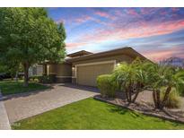 Charming single-story home featuring a lush green lawn, mature trees, and a brick-paved driveway at 7251 E Portobello Ave, Mesa, AZ 85212