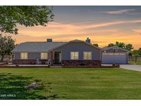 Charming single-story home with a brick foundation, well-manicured lawn, and a detached garage at sunset at 1551 E Longhorn Dr, Chandler, AZ 85286
