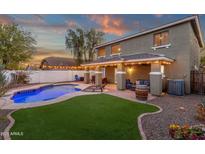An outdoor haven featuring a sparkling pool, inviting lounge area, and a covered patio with ambient lighting at 5919 S Banning St, Gilbert, AZ 85298